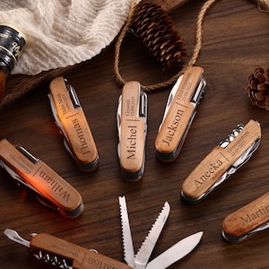 May include: A collection of personalized wooden pocket knives with various names and dates engraved on them. The knives are arranged on a dark wooden surface, alongside a bottle of liquor and decorative elements.