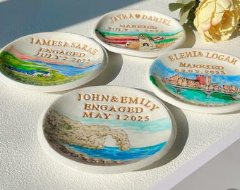 May include: Four small, oval ceramic dishes with hand-painted scenes and text. Each dish features a different landscape and the names and dates of a couple's engagement or marriage. The dishes are white with gold lettering and colorful illustrations.
