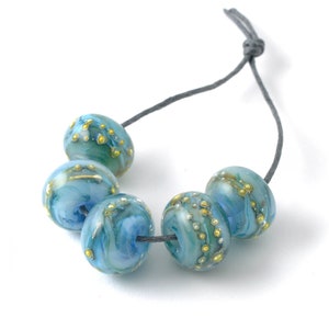 May include: A strand of five blue and gold glass beads with a grey cord. The beads have a marbled effect with gold flecks and swirls.