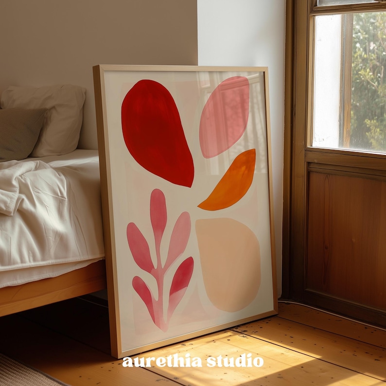 May include: A framed art print featuring abstract shapes in red, pink, and orange hues against a cream background. The artwork includes a large red shape, several pink leaf-like forms, and an orange curved shape. The text "aurethia studio" is printed at the bottom.