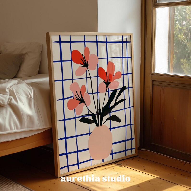 May include: A framed floral art print featuring a vase with pink flowers and black leaves. The background has a white grid with blue lines. The frame is light-colored wood. The text "aurethia studio" is at the bottom.