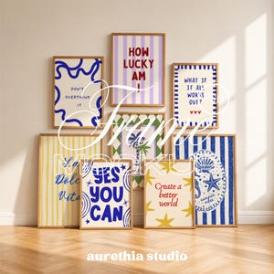 May include: A collection of eight rectangular wall art prints in light wood frames. The prints feature various designs including blue wavy lines, vertical stripes, palm trees, starfish, and text such as "Don't overthink it," "How lucky am I," and "Yes you can."