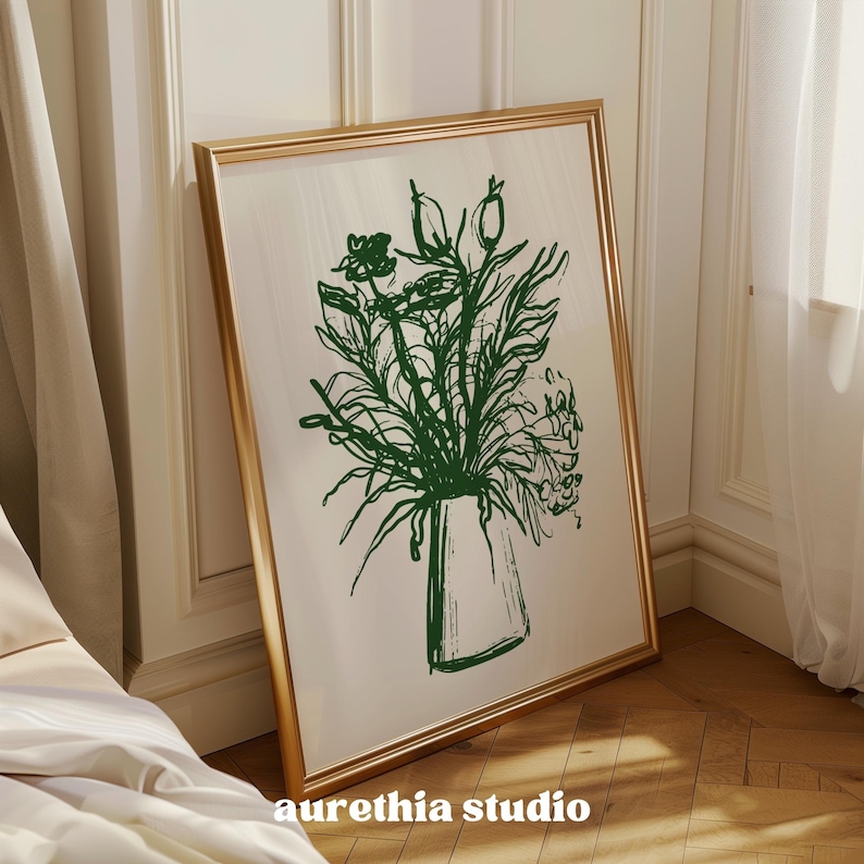 May include: A gold framed mirror with a green line drawing of a bouquet of flowers in a vase. The flowers are stylized and abstract.