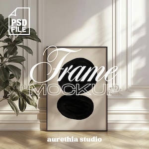 Può includere: Un mockup di cornice nera con uno sfondo beige e due forme astratte nere. Il testo "Frame Mockup" è scritto in bianco sulla cornice. Il testo "aurethia studio" è scritto in bianco nella parte inferiore della cornice.