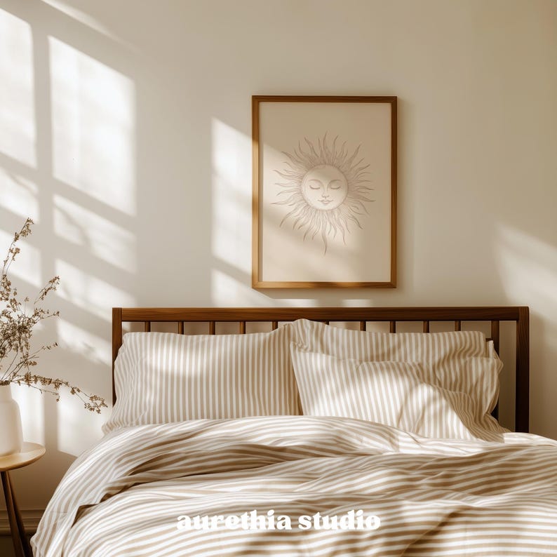 May include: A bedroom scene featuring a wooden bed frame, striped bedding, and a framed sun art print. The artwork has a beige background with a sun design. The bedding has a beige and white striped pattern. The room is bathed in natural light.