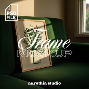 May include: A framed art print mockup with a green botanical illustration in a glass vase. The frame is light wood, and the print is displayed on a dark green sofa. The words "Frame Mockup" are overlaid on the image.
