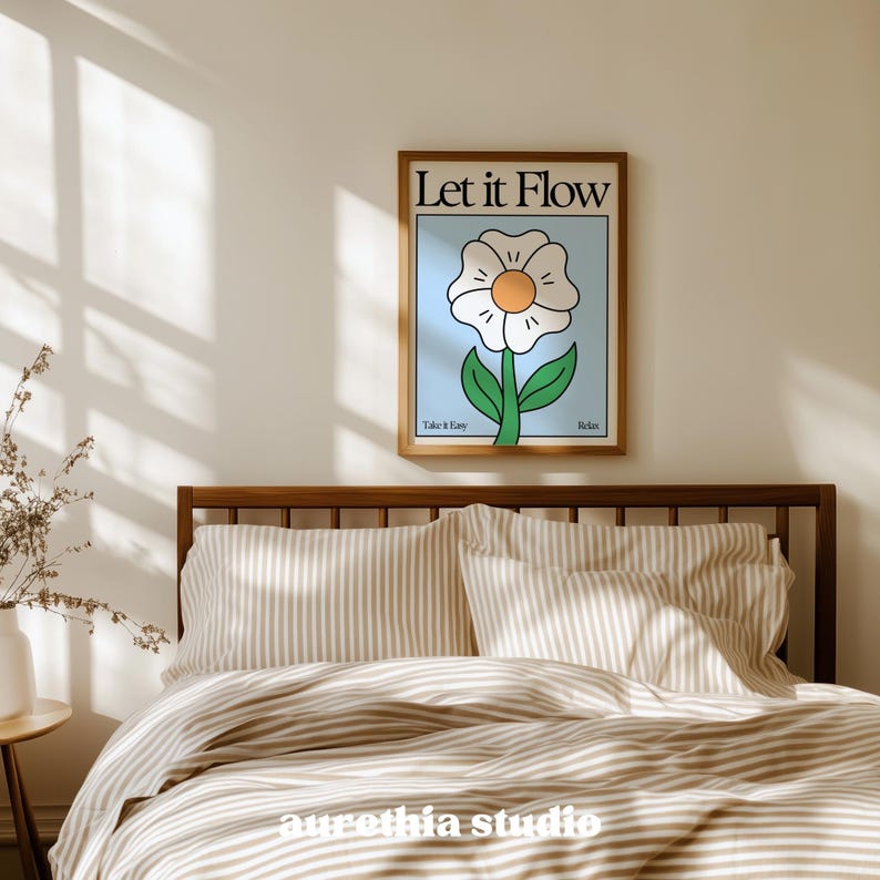 May include: A framed art print featuring a stylized white flower with an orange center and green stem against a light blue background. The print reads "Let it Flow" at the top and "Take it Easy" and "Relax" at the bottom. The print is displayed above a bed with striped bedding.