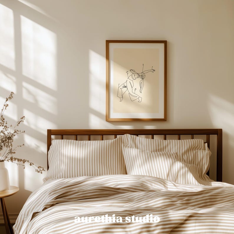 May include: A bedroom scene featuring a wooden bed frame, striped bedding, and a framed art print. The art print displays a minimalist line drawing of two figures. The text "aurethia studio" is visible on the bedding.