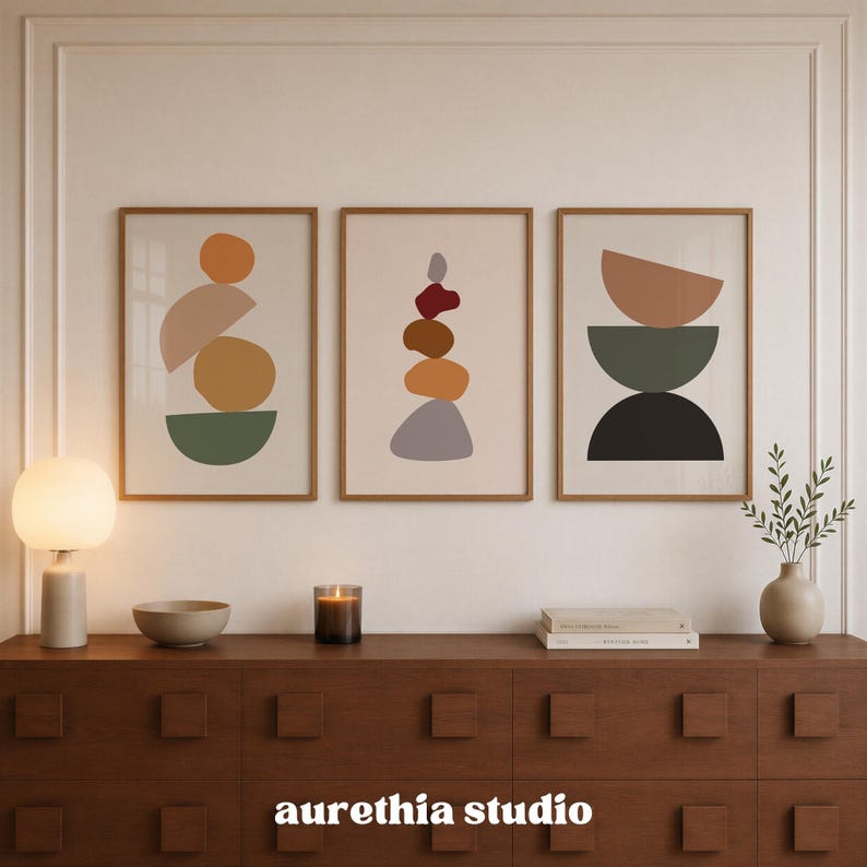 May include: Three framed vertical wall art prints featuring abstract geometric shapes in shades of orange, brown, green, and gray. The artwork displays stacked circular and semi-circular forms on a light background. The text aurethia studio is visible.