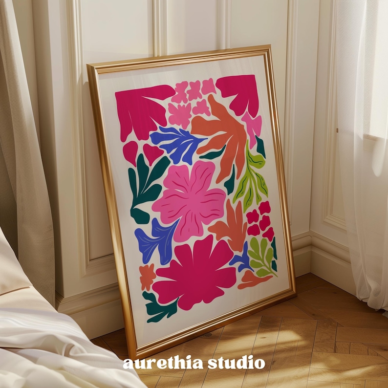 May include: A framed print with a colorful abstract floral design. The print features pink, red, orange, green, blue, and yellow flowers and leaves on a white background. The frame is gold.