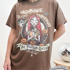 May include: Espresso-colored t-shirt featuring a graphic from "The Nightmare Before Christmas." The design includes Sally, pumpkins, and the text "The Pumpkin Queen." The shirt is a Comfort Colors brand.