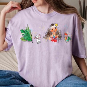 May include: A light purple short-sleeve t-shirt featuring a watercolor-style graphic print. The design includes a green tropical leaf, a small white pig, a female character with long brown hair and a yellow flower, and a colorful rooster.