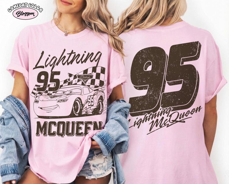 May include: A light pink t-shirt featuring a graphic of Lightning McQueen from the Cars movie. The front design includes the text "Lightning 95 McQueen" with an image of the race car. The back of the shirt displays a large "95" and "Lightning McQueen".