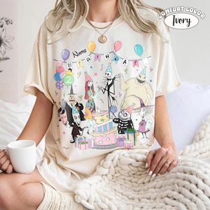 Op de afbeelding: Ivoor kleurig T-shirt met een verjaardagsfeestje met personages uit The Nightmare Before Christmas. Het ontwerp bevat een taart, ballonnen en de tekst "Name Birthday". Het shirt is gelabeld "Comfort Color Ivory".