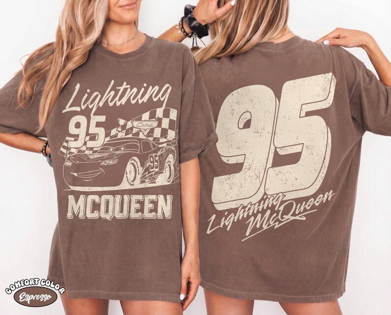 May include: Brown t-shirt featuring a graphic of Lightning McQueen race car with the number 95 and the text "Lightning McQueen". The back of the shirt displays a large number 95 and the text "Lightning McQueen".