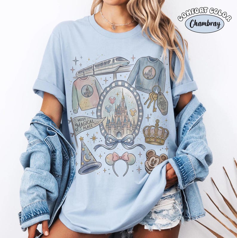 Puede incluir: Camiseta azul claro Comfort Colors Chambray con un gr&aacute;fico caprichoso. El dise&ntilde;o incluye un castillo, un tren, una corona, Mickey Mouse y otros elementos tem&aacute;ticos. Tambi&eacute;n aparecen las palabras "Most Magical Place".
