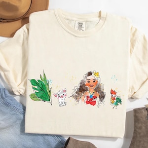 May include: A cream-colored short-sleeve t-shirt featuring a watercolor-style graphic print. The design displays a green tropical leaf, a small pig, a female character with long wavy hair and a flower, and a colorful rooster on the front center.