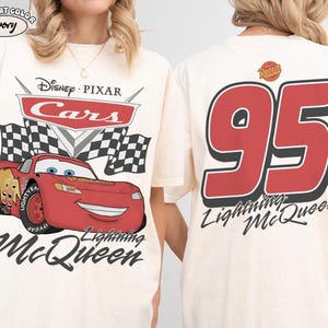 Pu&ograve; includere: T-shirt color avorio con Lightning McQueen di Cars di Disney Pixar. La parte anteriore presenta il logo Cars, bandiere a scacchi e Lightning McQueen sorridente. Il retro mostra il numero 95 e la scritta "Lightning McQueen."