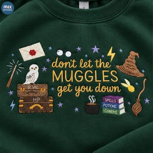 May include: A dark green sweatshirt featuring embroidered designs including a white owl, brown trunks, a sorting hat, a broom, a cauldron, and the text "don't let the MUGGLES get you down" in yellow, surrounded by small purple and blue stars.