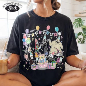 Op de afbeelding: Zwart Comfort Colors T-shirt met een kleurrijke verjaardagsafbeelding. Het ontwerp bevat personages, een taart, ballonnen en de tekst "Name Birthday 2". Het shirt heeft een relaxte pasvorm en een vintage uitstraling.