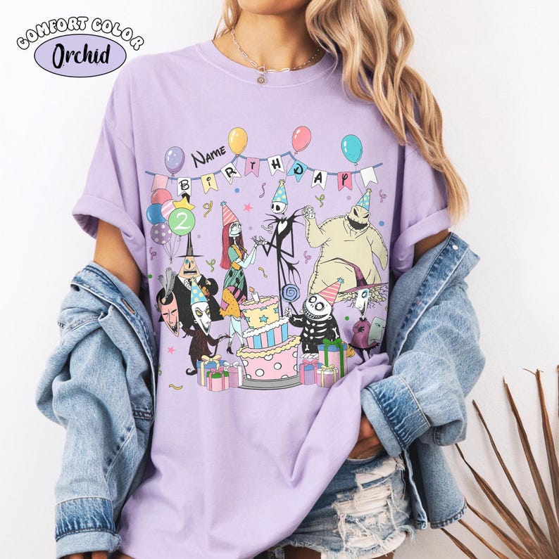 Op de afbeelding: Een lila Comfort Colors T-shirt met een verjaardagsfeestje met personages uit The Nightmare Before Christmas. Het ontwerp bevat een taart, ballonnen en de tekst "Name Birthday". Het shirt heeft een relaxte pasvorm.