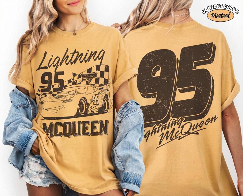 May include: Mustard-colored t-shirt featuring a graphic of Lightning McQueen from the Cars movie. The front design includes the text "Lightning 95 McQueen" and an image of the race car. The back of the shirt displays a large "95" and "Lightning McQueen".