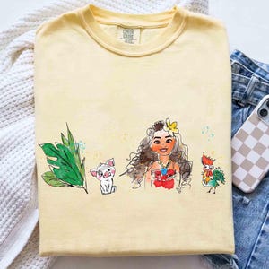 May include: A pale yellow short-sleeve t-shirt featuring a watercolor-style graphic print. The design displays a green tropical leaf, a small white pig, a long-haired character with a yellow flower in their hair, and a colorful rooster.