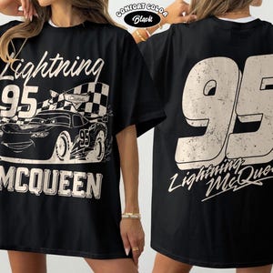 May include: Black Lightning McQueen t-shirt with a large graphic on the front featuring the number 95, a race car, and the name McQueen. The back of the shirt also has the number 95 and the name Lightning McQueen.