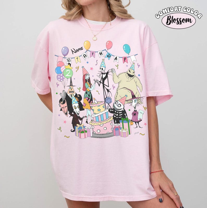 Op de afbeelding: Roze Comfort Colors T-shirt met een verjaardagsfeestje met personages uit The Nightmare Before Christmas. Het ontwerp bevat een taart, ballonnen en de woorden "Name Birthday". Het shirt heeft een relaxte pasvorm.