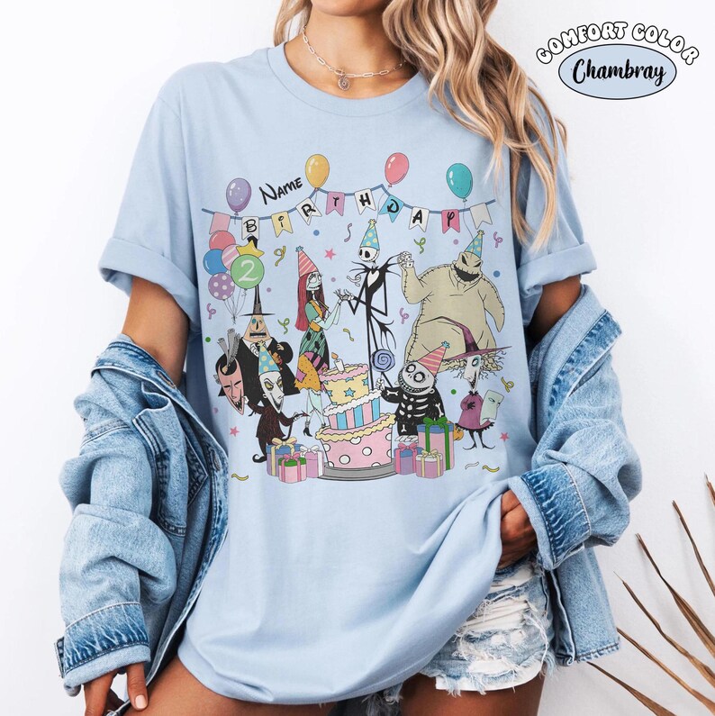 Op de afbeelding: Lichtblauw T-shirt met een kleurrijk verjaardagsfeestontwerp met animatiefiguren. Het ontwerp bevat een taart, ballonnen en de tekst "NAME BIRTHDAY". Het shirt is gemaakt van een zacht, comfortabel materiaal.