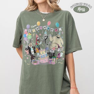 Op de afbeelding: Olijfgroen T-shirt met een verjaardagsfeestje, personages, ballonnen en een taart. De tekst "Name Birthday 2" staat op een banner. Het shirt is een Comfort Colors Moss.
