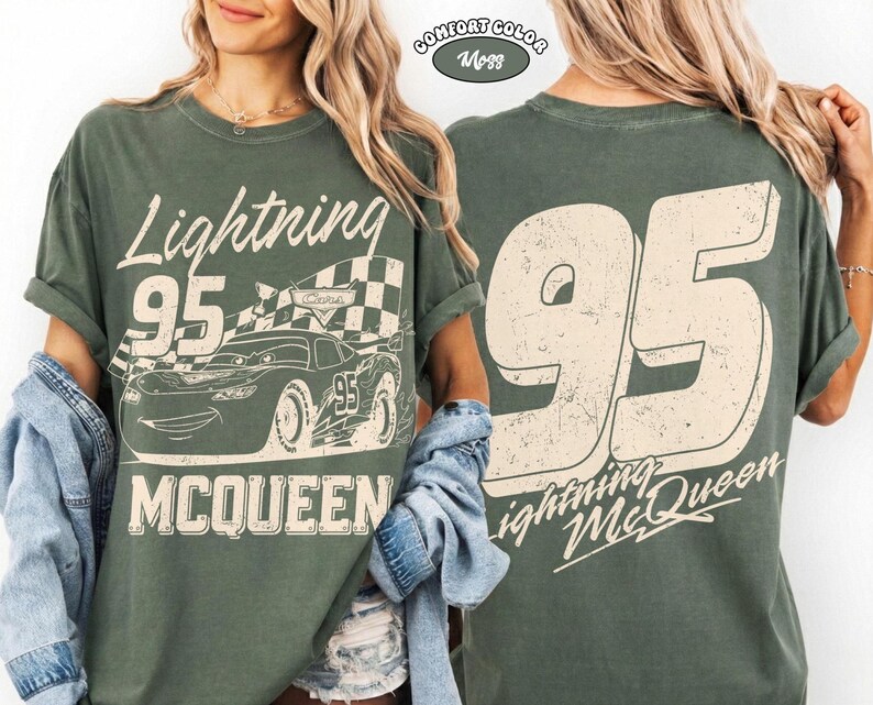 May include: A green t-shirt featuring Lightning McQueen from the Cars movie. The front graphic includes the text "Lightning 95 McQueen" with a checkered flag and a cartoon car. The back of the shirt displays a large "95" and "Lightning McQueen".