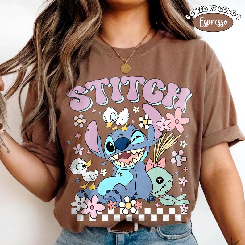 May include: Brown t-shirt featuring a graphic of the Disney character Stitch, with flowers and ducks. The word "STITCH" is printed in large letters. The shirt is labelled "Comfort Color Espresso".
