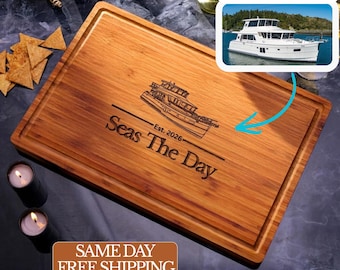 May include: A rectangular bamboo cutting board featuring a laser-engraved illustration of a motor yacht, the text "Seas The Day", and the text "Est. 2026". The board has a grooved perimeter channel and a natural light brown wood grain finish.