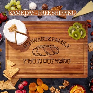 May include: A rectangular bamboo cutting board featuring an engraved illustration of a braided loaf of bread, the text "SCHWARTZ FAMILY", and Hebrew text. The board is surrounded by various food items including grapes, cheese, nuts, and crackers.