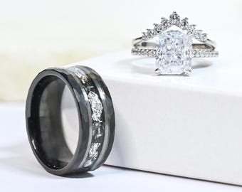 May include: A black and white wedding band with a diamond-like design and a silver ring with a large, square-shaped diamond.