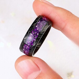 May include: A black ring with a purple glitter inlay. The ring has a grooved design.