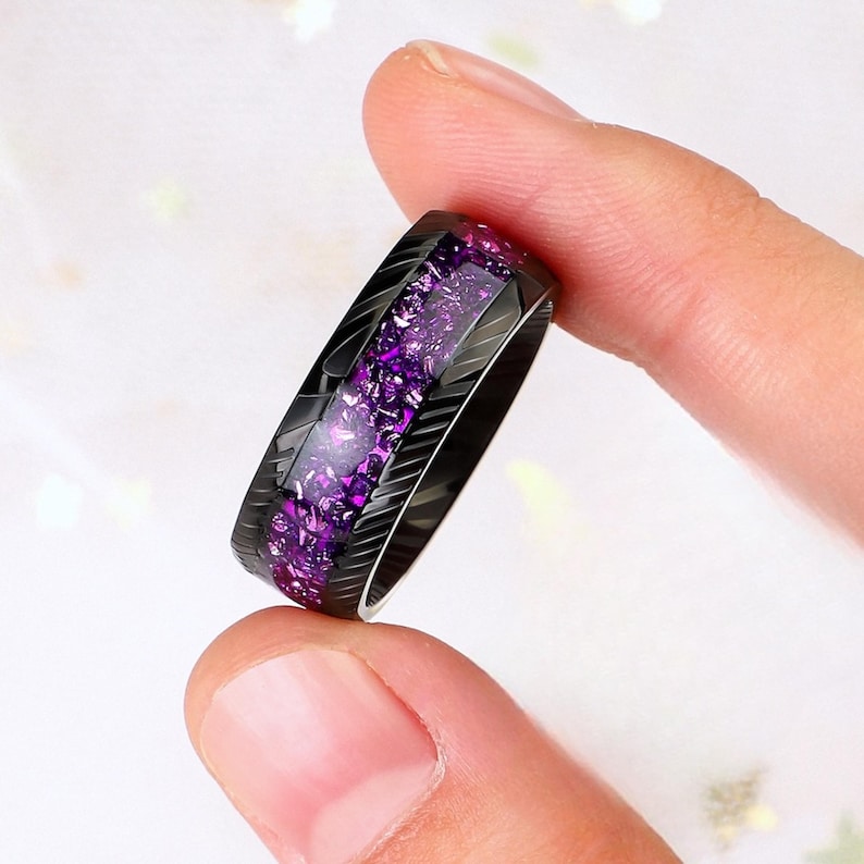 May include: A black ring with a purple glitter inlay. The ring has a grooved design.