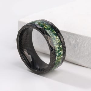 May include: A black ring with a green and white patterned inlay. The ring has a textured, grooved surface.