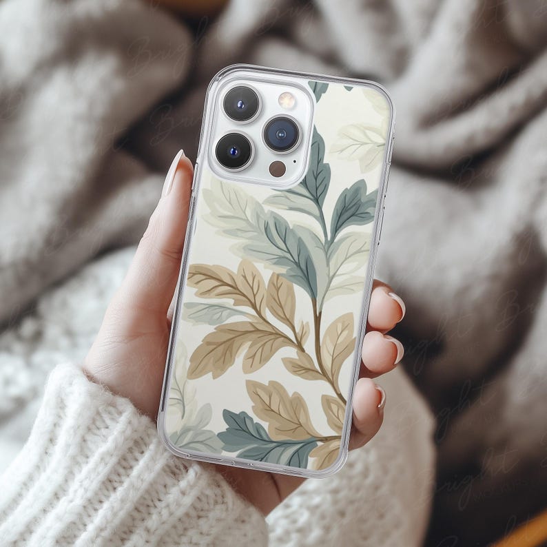 Phone case mockup of a clear phone case held by a girl's hand that's wearing a wool white sweater, in front of a cozy blanket. Works in Photoshop, Photopea and Canva.