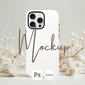 Może przedstawiać: Biała mockupa etui na iPhone'a z czarnym obiektywem aparatu i tekstem "Mockup" napisanym brązowym kursywą. Etui leży na białym tle z białymi kwiatami w tle. Tekst "Ps Canva" jest nadrukowany na spodzie etui.