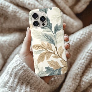 Silicone Phone Case Mockup of an iPhone held by a young woman's hand in front of some cozy beige wool blankets. Works in Photoshop, Photopea and Canva.