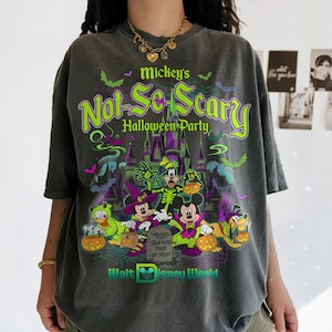 May include: A charcoal gray t-shirt featuring a graphic print of Mickey Mouse and friends in Halloween costumes. The text reads Mickey's Not-So-Scary Halloween Party and Walt Disney World. The design includes a castle, bats, and pumpkins.