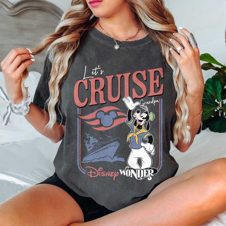 May include: Dark gray t-shirt with the text "Let's Cruise Grandpa" and a graphic of a cruise ship and Goofy waving. The design includes the Disney Wonder logo and a Mickey Mouse head. The shirt has a vintage, worn look.