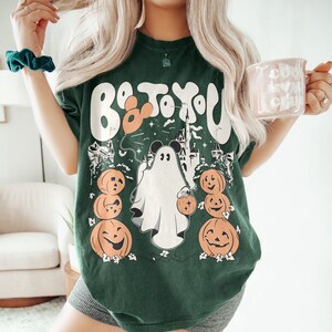 May include: Dark green t-shirt with a Halloween graphic. The design includes a ghost with Mickey Mouse ears, pumpkins, and the text "Boo to You". The shirt is a casual, comfortable style.