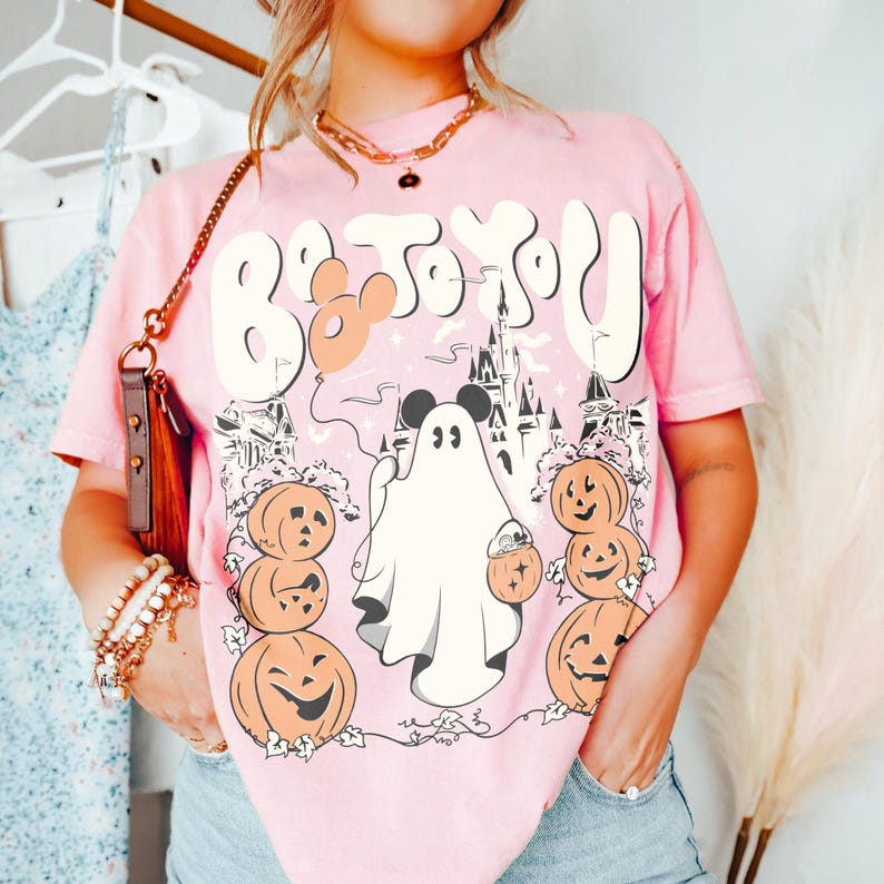 May include: Pale pink t-shirt with a Halloween graphic. The design includes a ghost, pumpkins, and the text "Boo to You". The tee has a relaxed fit and short sleeves, ideal for the spooky season.