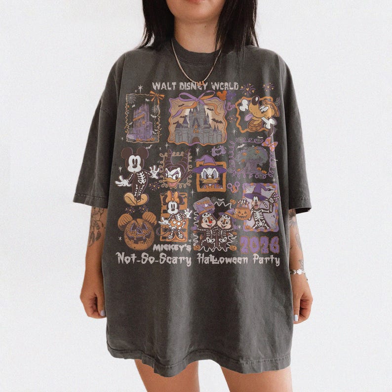 May include: Dark gray t-shirt featuring a Halloween-themed design with various Disney characters. The shirt includes the text "WALT DISNEY WORLD" and "Mickey's Not-So-Scary Halloween Party 2026". The design incorporates purple and orange accents.