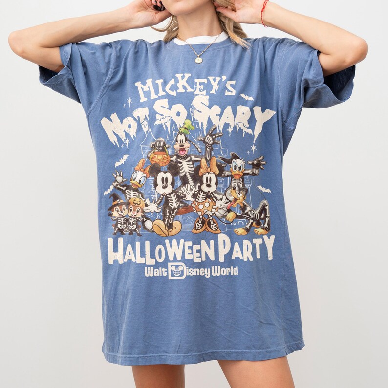 May include: Blue t-shirt featuring a graphic of Mickey Mouse and friends in skeleton costumes, with the text "Mickey's Not So Scary Halloween Party" and "Walt Disney World". The shirt has a white collar.