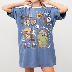 May include: Blue t-shirt with a graphic design featuring characters from "The Nightmare Before Christmas." The design includes Jack Skellington, Sally, and Oogie Boogie. The shirt has a relaxed fit and is made of a soft material.