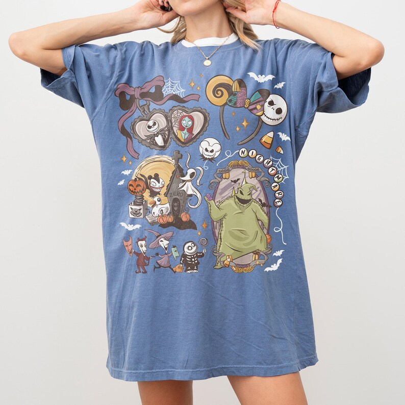 May include: Blue t-shirt with a graphic design featuring characters from "The Nightmare Before Christmas." The design includes Jack Skellington, Sally, and Oogie Boogie. The shirt has a relaxed fit and is made of a soft material.